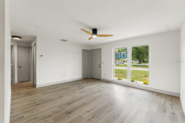 7400 Belvedere Ter, New Port Richey, FL 34655 - unfurnished room featuring baseboards, a ceiling fan, light wood-type flooring, and a textured ceiling