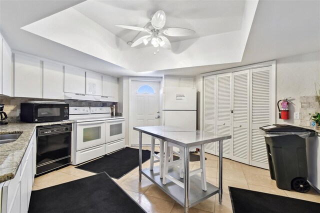 10216 Regal Dr Unit 310, Largo, FL 33774 - kitchen with black appliances, a tray ceiling, under cabinet range hood, white cabinetry, and backsplash