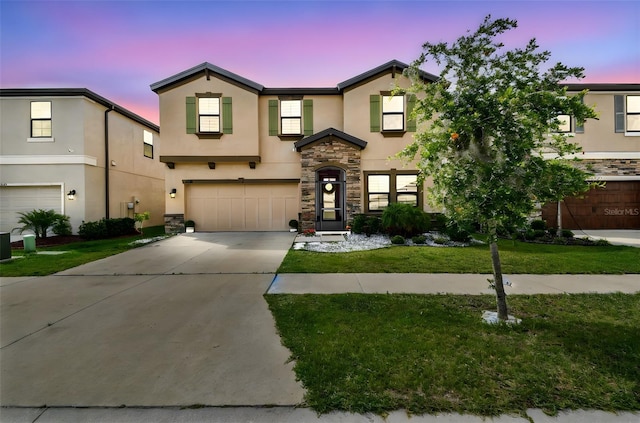 view of front of house with stucco siding, an attached garage, stone siding, concrete driveway, and a lawn