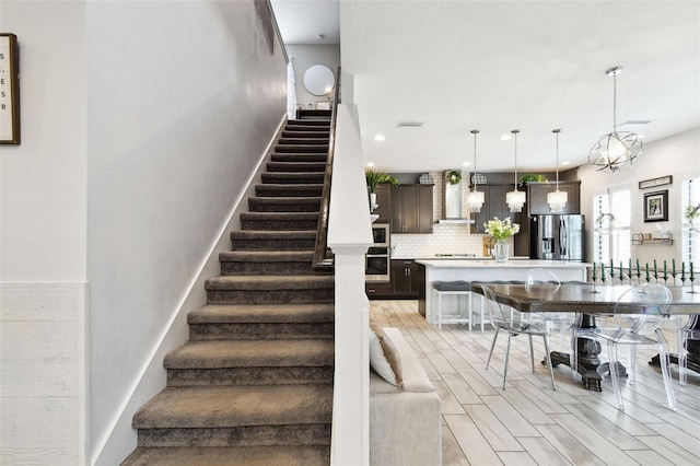 staircase with wood finished floors and recessed lighting