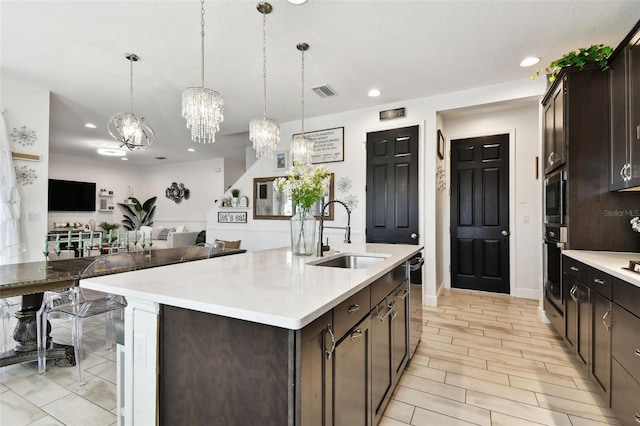 kitchen with a sink, stainless steel appliances, a chandelier, dark brown cabinetry, and recessed lighting