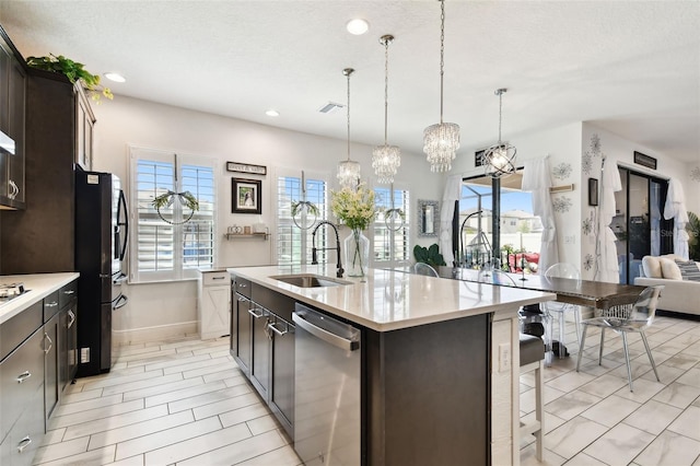 kitchen featuring a sink, stainless steel dishwasher, refrigerator with ice dispenser, a kitchen breakfast bar, and light countertops