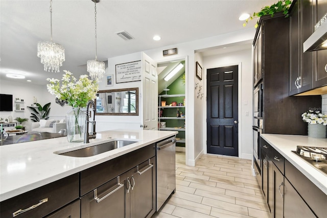 kitchen featuring a sink, exhaust hood, stainless steel appliances, a chandelier, and dark brown cabinets