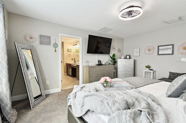 bedroom with light carpet, baseboards, and ensuite bathroom