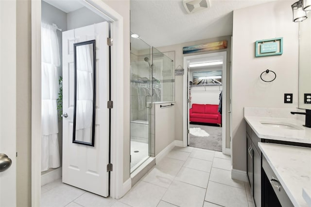 full bathroom with a stall shower, vanity, a walk in closet, and baseboards