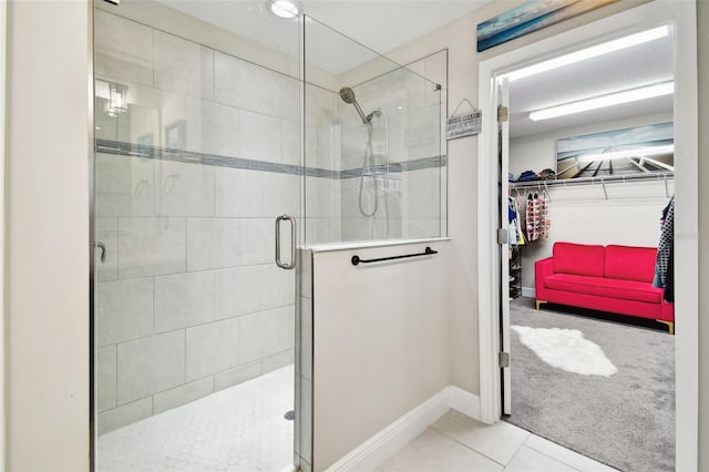 full bathroom featuring a shower stall, a walk in closet, tile patterned floors, and baseboards