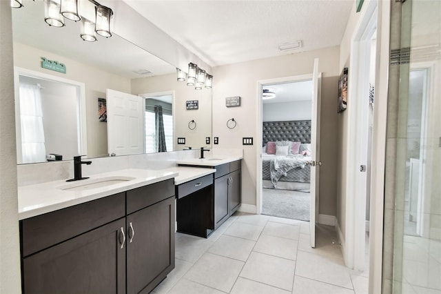 ensuite bathroom with vanity, baseboards, and tile patterned floors