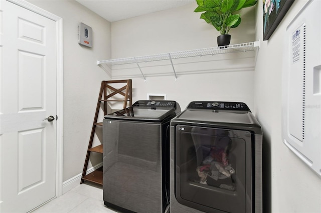 washroom with independent washer and dryer, tile patterned floors, and baseboards