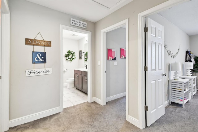 corridor featuring light carpet, baseboards, and a sink