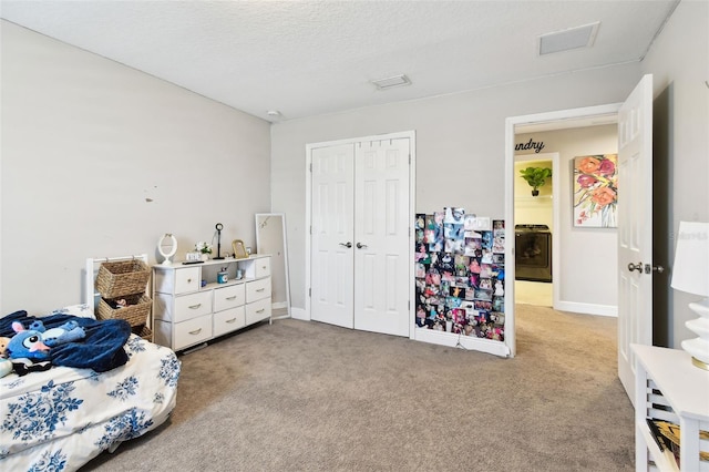 bedroom featuring carpet flooring, washer / clothes dryer, a closet, baseboards, and a textured ceiling