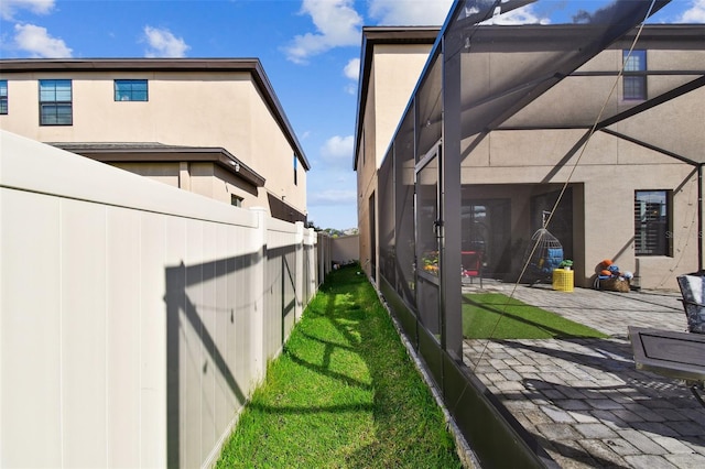 view of side of property featuring stucco siding, a patio, and glass enclosure