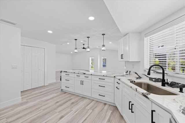 5507 Nimitz Rd, New Port Richey, FL 34652 - kitchen featuring a sink, recessed lighting, white cabinets, a peninsula, and light stone counters