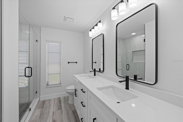 5507 Nimitz Rd, New Port Richey, FL 34652 - full bathroom featuring wood finished floors, toilet, a marble finish shower, baseboards, and double vanity