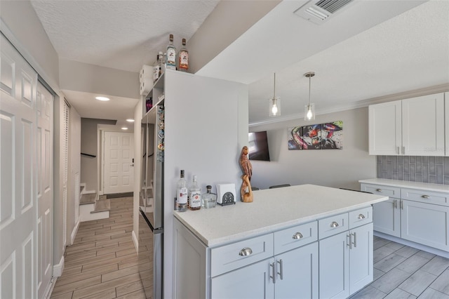 kitchen featuring decorative backsplash, light countertops, wood finish floors, hanging light fixtures, and recessed lighting
