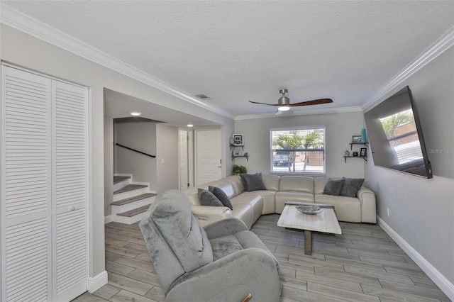 living room featuring stairway, wood finish floors, baseboards, a textured ceiling, and ornamental molding