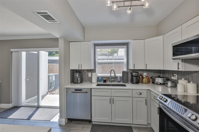 kitchen featuring a sink, appliances with stainless steel finishes, decorative backsplash, light countertops, and white cabinetry