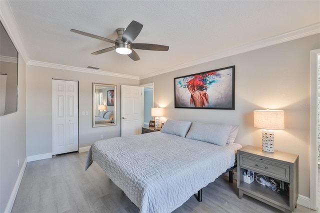 bedroom featuring wood finished floors, baseboards, ornamental molding, a closet, and a ceiling fan