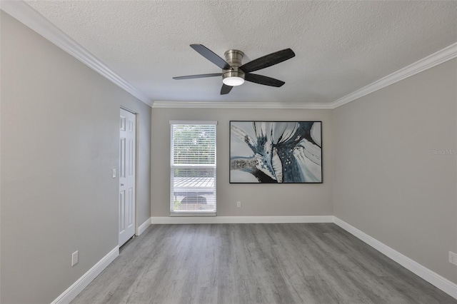 unfurnished room with wood finished floors, a textured ceiling, a ceiling fan, ornamental molding, and baseboards