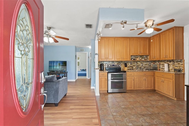 kitchen with double oven range, ceiling fan, decorative backsplash, and light stone counters