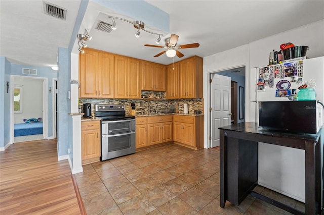 kitchen featuring double oven range, a ceiling fan, decorative backsplash, and freestanding refrigerator