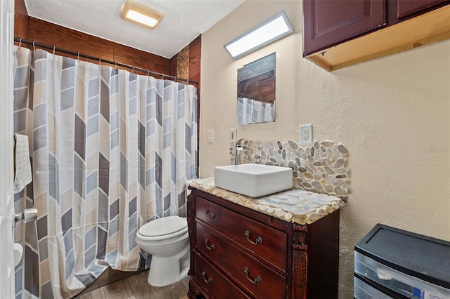 full bath with wood finished floors, toilet, vanity, curtained shower, and a textured wall