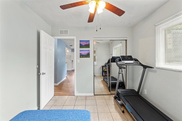 workout room with light tile patterned floors, a ceiling fan, and baseboards