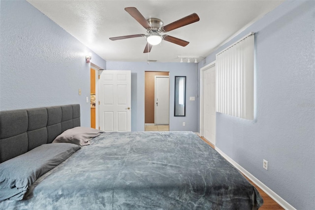 bedroom with baseboards, a textured wall, and ceiling fan