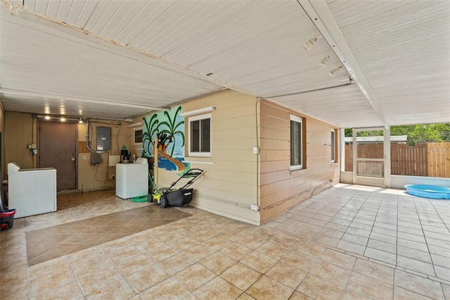 view of patio featuring washer / dryer, electric panel, and fence