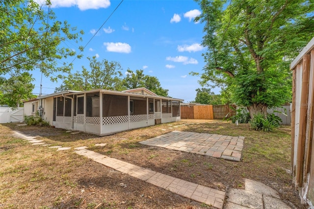 back of property with a sunroom, a fenced backyard, a gate, and a patio