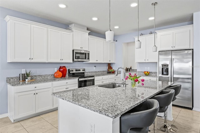 3071 Marine Grass Dr, Wimauma, FL 33598 - kitchen with stainless steel appliances, a sink, light tile patterned flooring, white cabinets, and recessed lighting