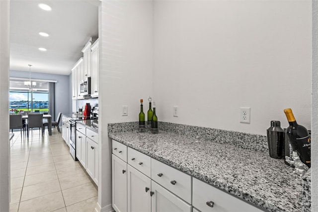 3071 Marine Grass Dr, Wimauma, FL 33598 - kitchen featuring stainless steel appliances, white cabinets, light tile patterned flooring, recessed lighting, and light stone countertops