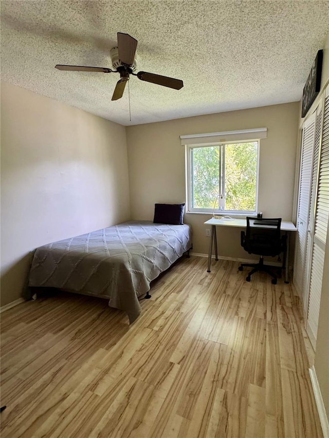 220 Cypress Ln Unit 220, Oldsmar, FL 34677 - bedroom with light wood finished floors, a textured ceiling, a closet, ceiling fan, and a desk