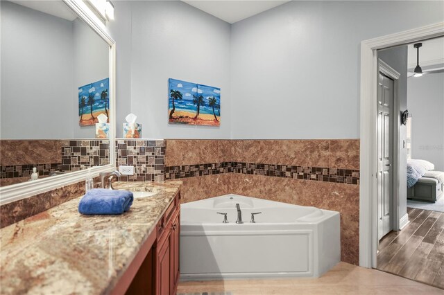 205 Brightwater Dr Unit 101, Clearwater Beach, FL 33767 - ensuite bathroom with a bath, vanity, tile walls, a wainscoted wall, and tile patterned flooring