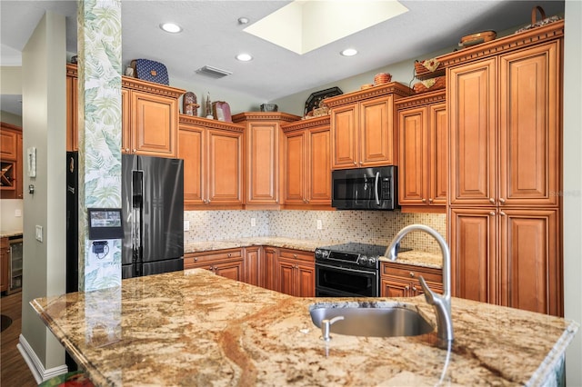205 Brightwater Dr Unit 101, Clearwater Beach, FL 33767 - kitchen featuring freestanding refrigerator, a skylight, a sink, light stone counters, and recessed lighting