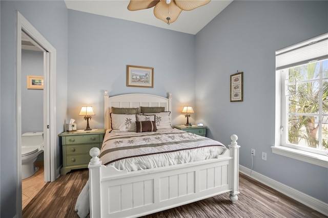 205 Brightwater Dr Unit 101, Clearwater Beach, FL 33767 - bedroom with dark wood-type flooring, vaulted ceiling, ensuite bath, and baseboards