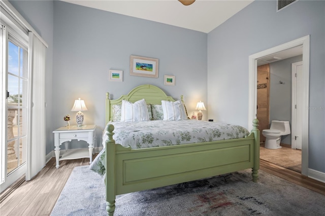 205 Brightwater Dr Unit 101, Clearwater Beach, FL 33767 - bedroom featuring wood finished floors, baseboards, access to exterior, and ensuite bathroom