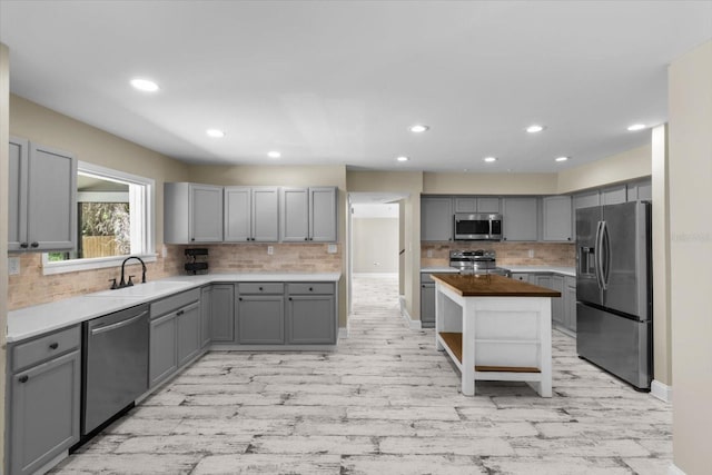 kitchen with stainless steel appliances, gray cabinets, a sink, decorative backsplash, and recessed lighting