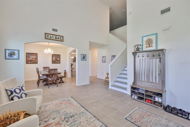 11924 Brighton Knoll Loop, Riverview, FL 33579 - living room featuring arched walkways, a chandelier, a high ceiling, tile patterned flooring, and stairs