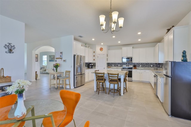 11924 Brighton Knoll Loop, Riverview, FL 33579 - kitchen featuring appliances with stainless steel finishes, arched walkways, tasteful backsplash, a kitchen bar, and recessed lighting