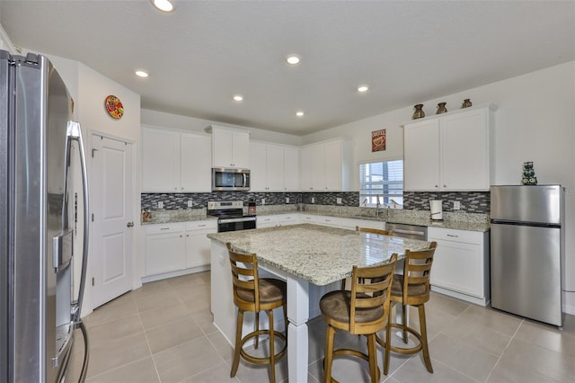 11924 Brighton Knoll Loop, Riverview, FL 33579 - kitchen featuring stainless steel appliances, a center island, decorative backsplash, white cabinets, and recessed lighting