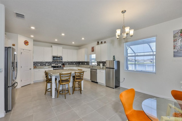 11924 Brighton Knoll Loop, Riverview, FL 33579 - kitchen with stainless steel appliances, backsplash, a chandelier, a breakfast bar, and white cabinetry