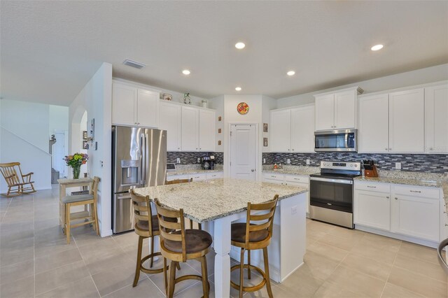 11924 Brighton Knoll Loop, Riverview, FL 33579 - kitchen featuring appliances with stainless steel finishes, a kitchen island, backsplash, white cabinets, and recessed lighting