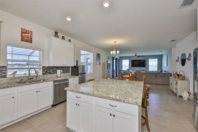 11924 Brighton Knoll Loop, Riverview, FL 33579 - kitchen with stainless steel appliances, light tile patterned floors, a sink, tasteful backsplash, and white cabinets