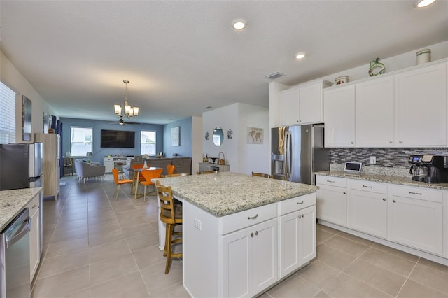11924 Brighton Knoll Loop, Riverview, FL 33579 - kitchen with stainless steel appliances, open floor plan, a chandelier, white cabinets, and backsplash