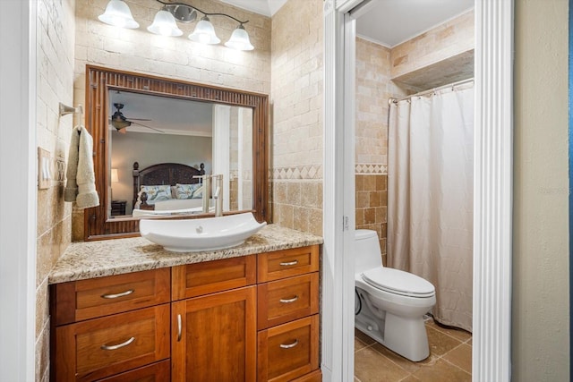 ensuite bathroom featuring toilet, tile patterned floors, vanity, tile walls, and crown molding