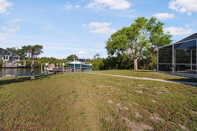 view of green lawn with boat lift, a dock, a lanai, and a water view