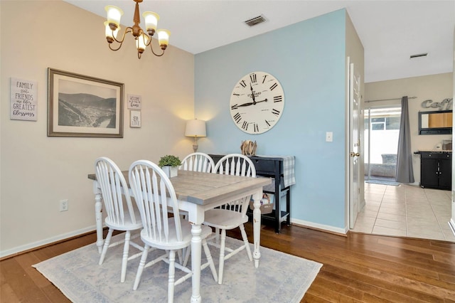 dining area with a chandelier, hardwood / wood-style floors, and baseboards