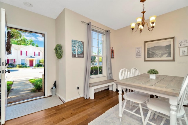 dining area with a chandelier, wood finished floors, and baseboards