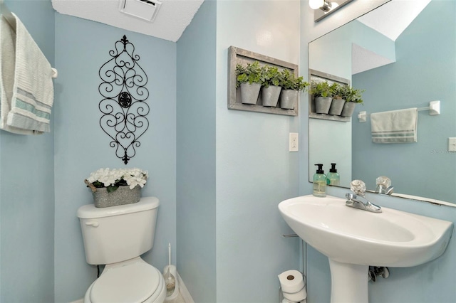 half bath featuring toilet, baseboards, and a sink