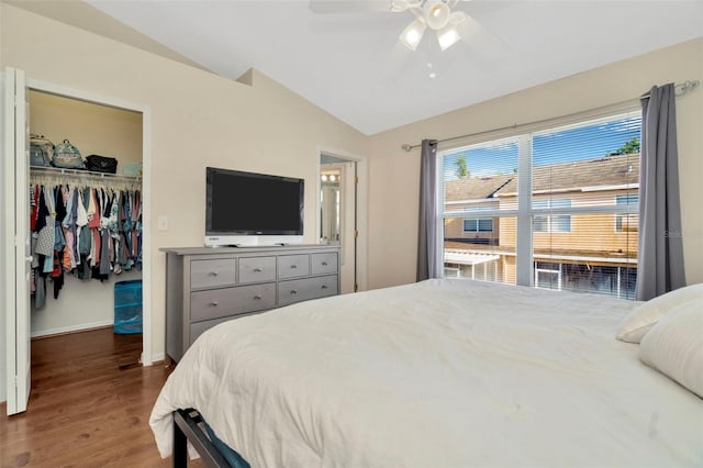bedroom with vaulted ceiling, a walk in closet, wood finished floors, a closet, and multiple windows